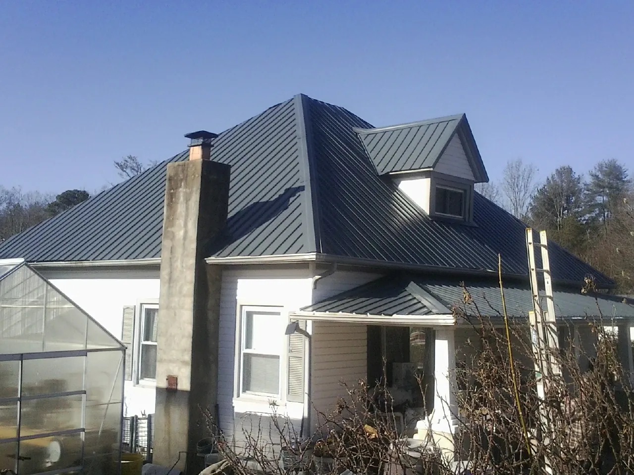 Dark blue standing seam metal roof on a white farmhouse with dormer — Slate & Tile Roof Repair by Roofing Brothers in Maury City