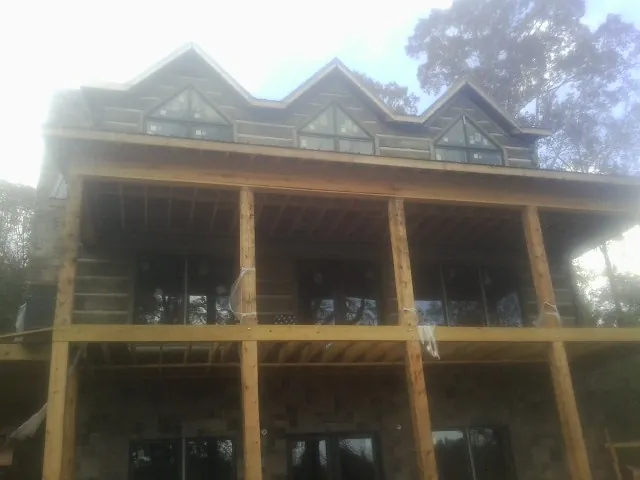 Dormers and porch framing on a large log home under construction — Roof Coating work by our crew in Maury City