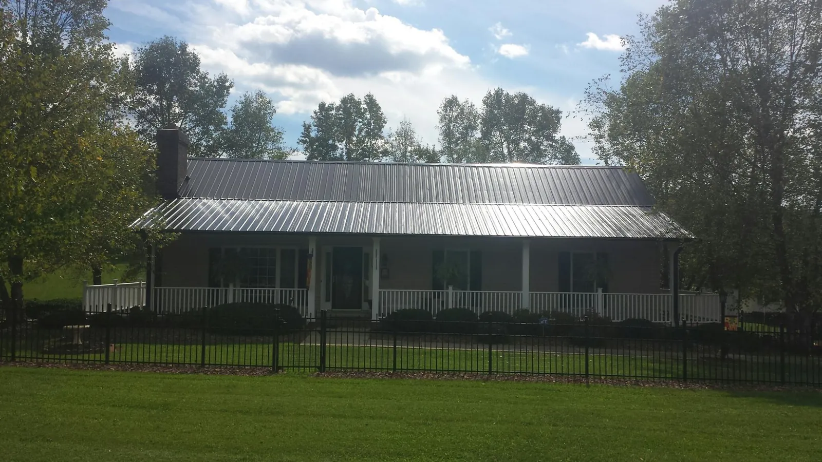 Gray metal roof on a brick ranch with a full width front porch — Gutter Guard Installation work by our crew in Maury City