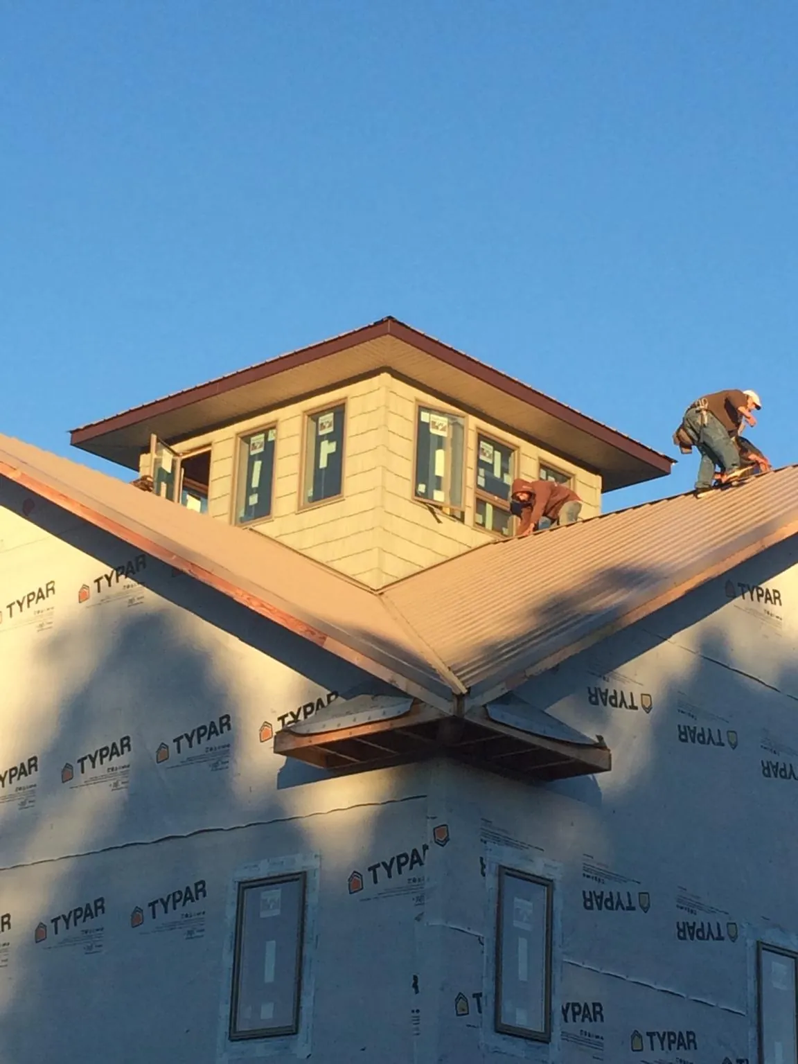 Roofers working around a rooftop cupola on a new metal roof at sunset — Roof Waterproofing in Maury City by Roofing Brothers